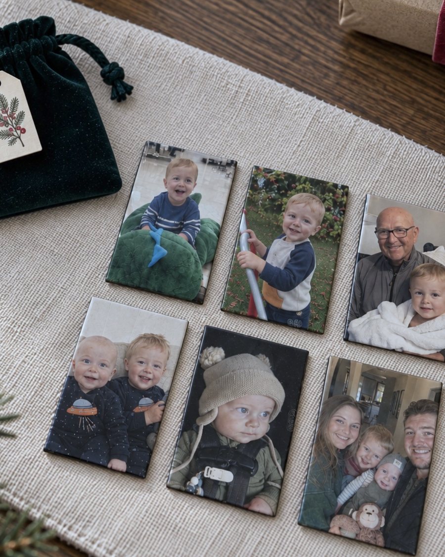 A green velvet gift bag with a holiday gift tag, beside six photo magnets of kids, a grandpa and a family